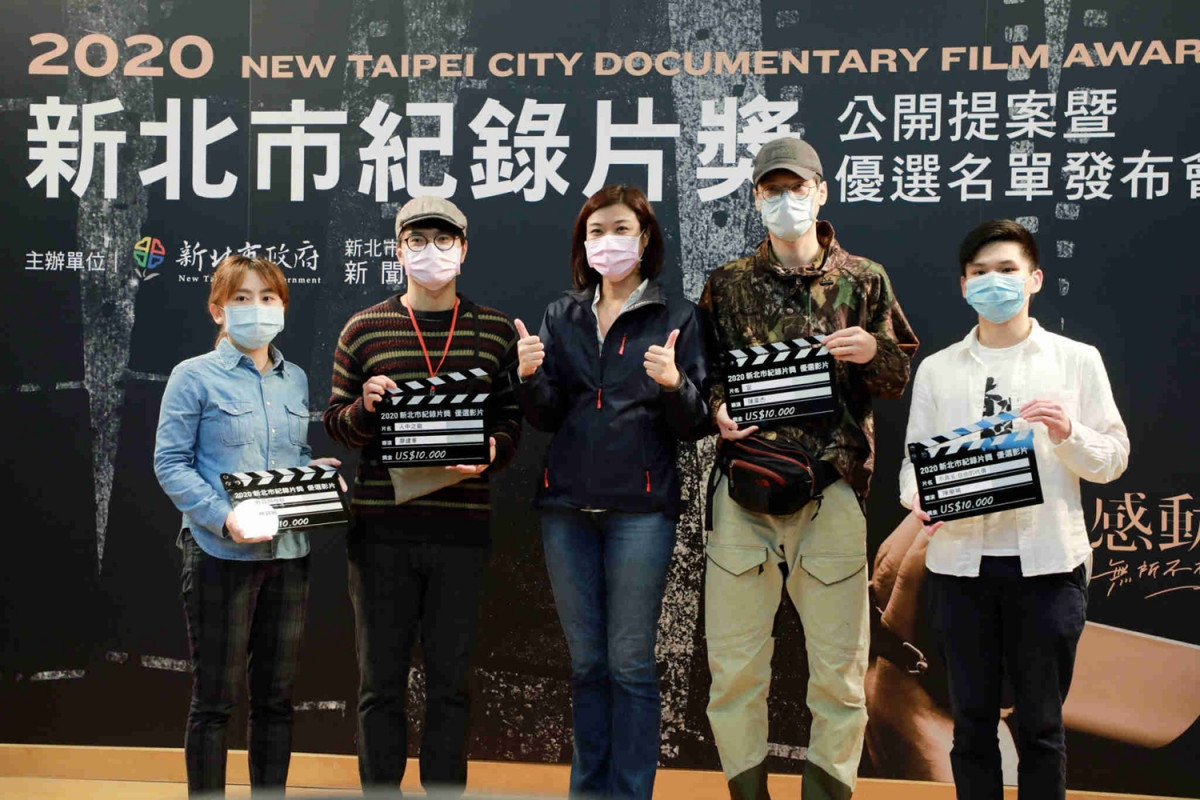 Director of Information Department Chiang Zhi-wei takes a photo with the directors of 12 selected films. 